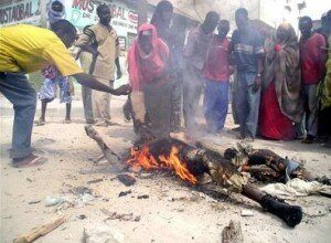 Mogadishu residents converge around the body of a government soldier who caught fire during intense fighting.