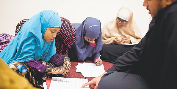 Photo | Jenn Ackerman I The New York Times Kassim Busuri (right) helps young Somali girls with their homework as part of a tutoring programme at the Daâwah Islamic Centre in St. Paul, Minneapolis on November 15, 2010