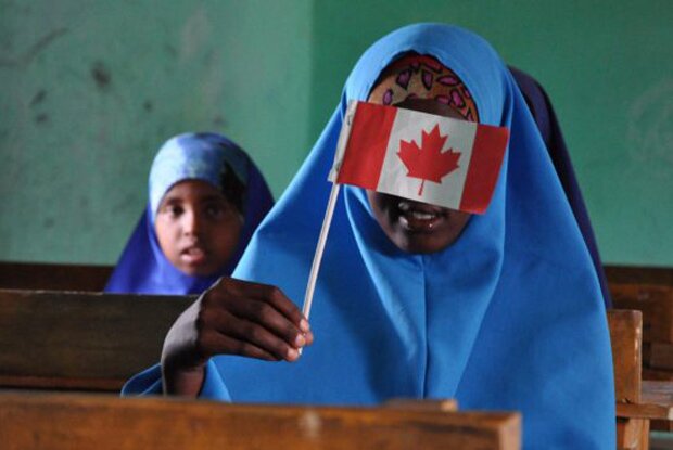 A young student hides her face with a Canadian flag at the Daynille school on the outskirts of Mogadishu. The school, which opened in 2013, was built thanks to remittances and fundraising in Canada.